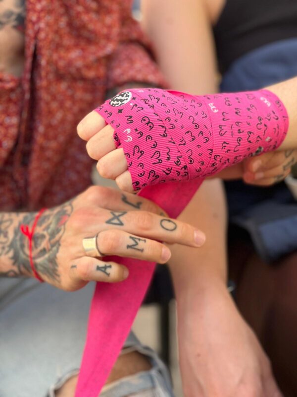 mujer llevando vendas de boxeo rosa neón con diseño de tetas con purpurina